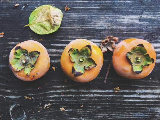 persimmons on the wooden table by Timmy333